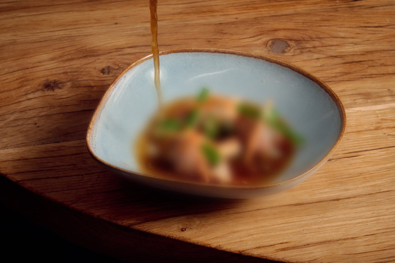 Duck Tea being poured into the bowl, the food in it softly blurred