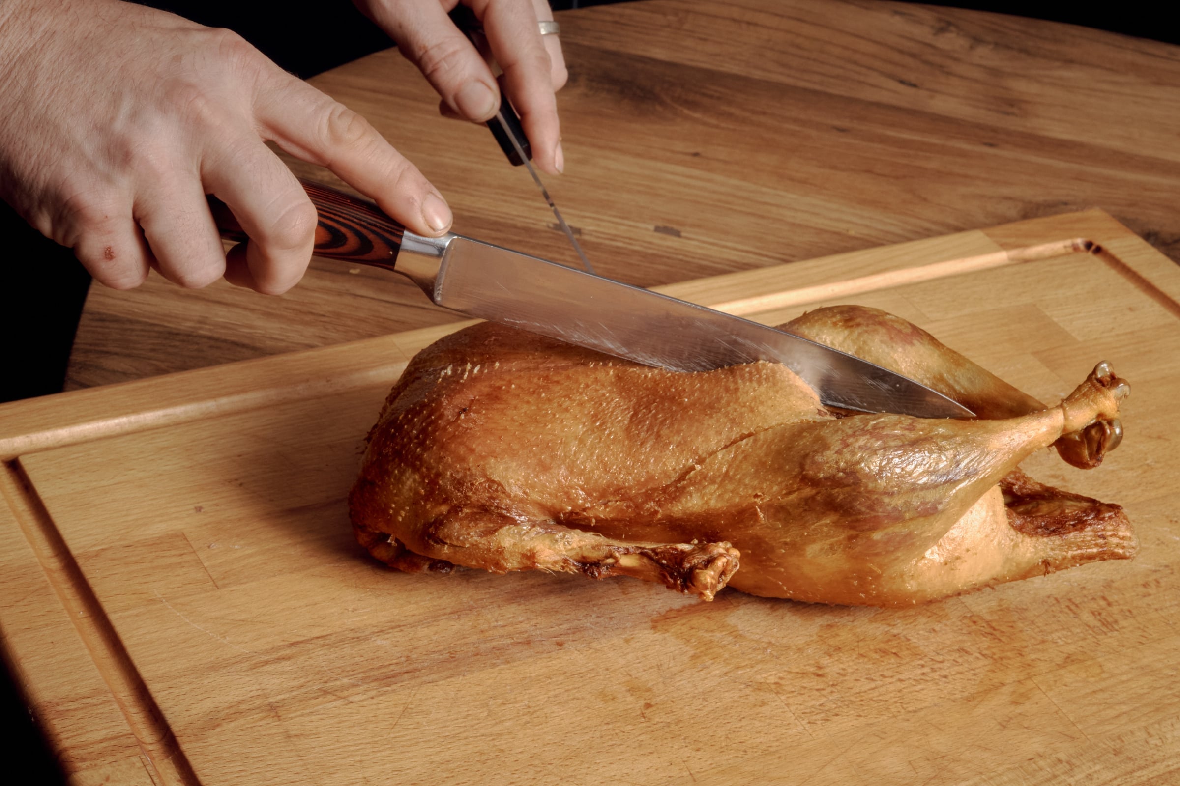 Die Vierländer Ente auf dem Holzbrett, das Messer setzt an